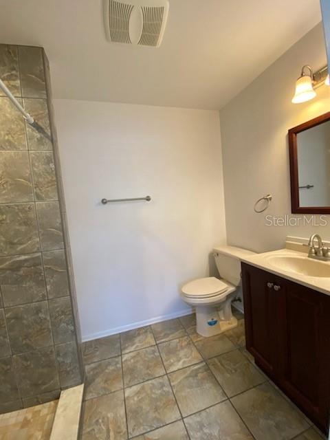A bathroom features a tiled shower, a toilet, and a dark wood vanity with a mirror — 512 BARCELONA AVENUE UNIT 4, VENICE, FL