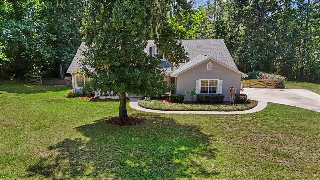 A gray house with white shutters sits on a grassy lot surrounded by trees — 5045 SW 2ND AVENUE, OCALA, FL