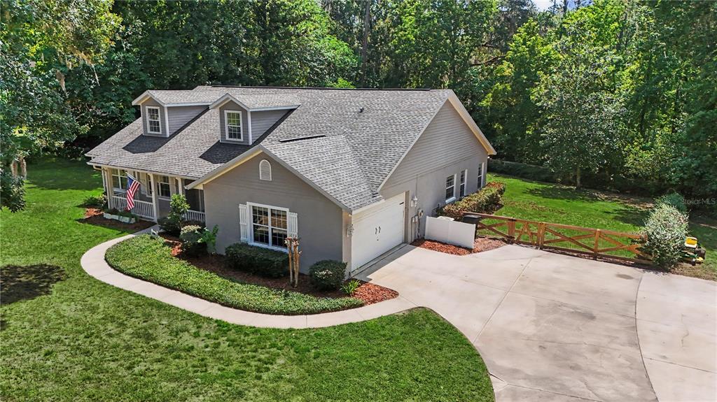 An elevated view of a gray house with a garage, dormer windows, and a lawn — 5045 SW 2ND AVENUE, OCALA, FL