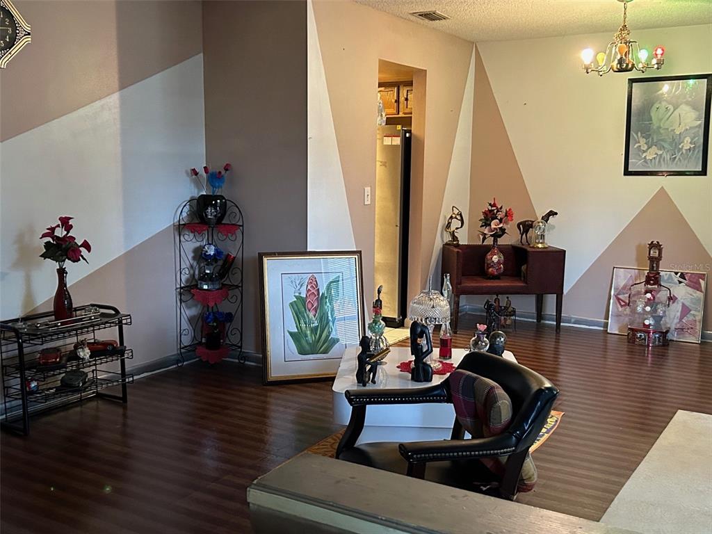 A living room features dark wood-look flooring, geometric wall paint, and various decorative furniture pieces — 2932 SILVER RIDGE DRIVE, ORLANDO, FL