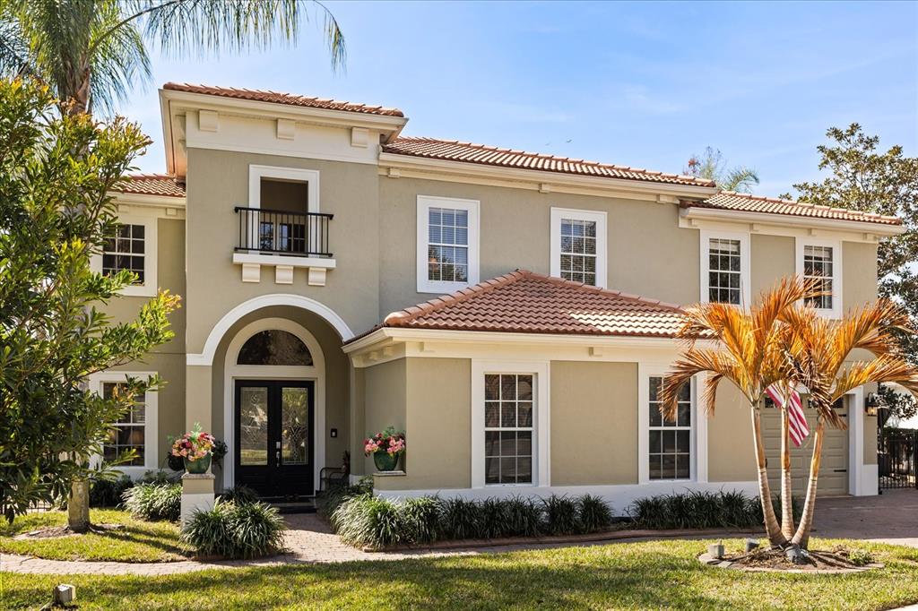 A two-story house with a stucco exterior, tile roof, arched entryway, and a small balcony — 2450 DAHLGREN WAY, WINTER GARDEN, FL