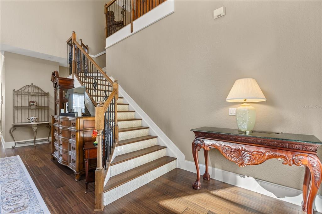 A foyer features a wooden staircase with patterned risers, dark wood flooring, and ornate furniture — 2450 DAHLGREN WAY, WINTER GARDEN, FL