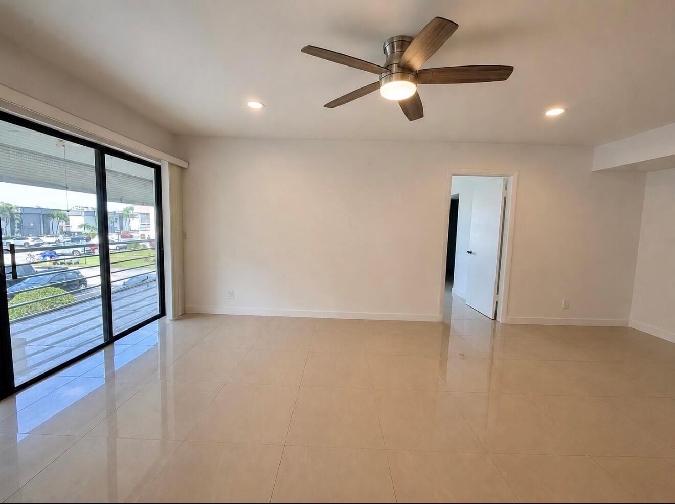 An empty room with beige tile flooring, a ceiling fan, and a sliding glass door — 514 Piedmont K, Delray Beach FL 33446, DELRAY BEACH, FL
