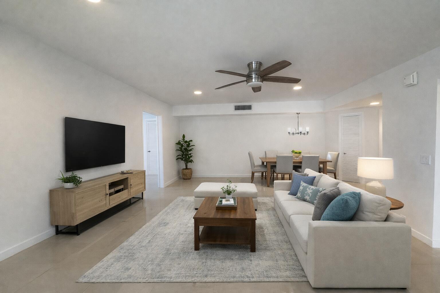 A living room features a light-colored sofa, a wooden coffee table, and a wall-mounted television — 514 Piedmont K, Delray Beach FL 33446, DELRAY BEACH, FL