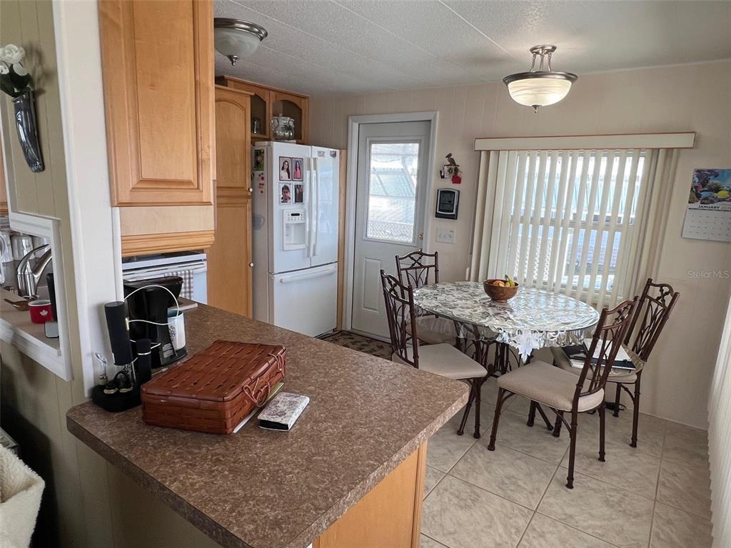 A kitchen with light wood cabinets, a brown countertop, and a dining area with seating — 37 PINDO PALM STREET W, LARGO, FL