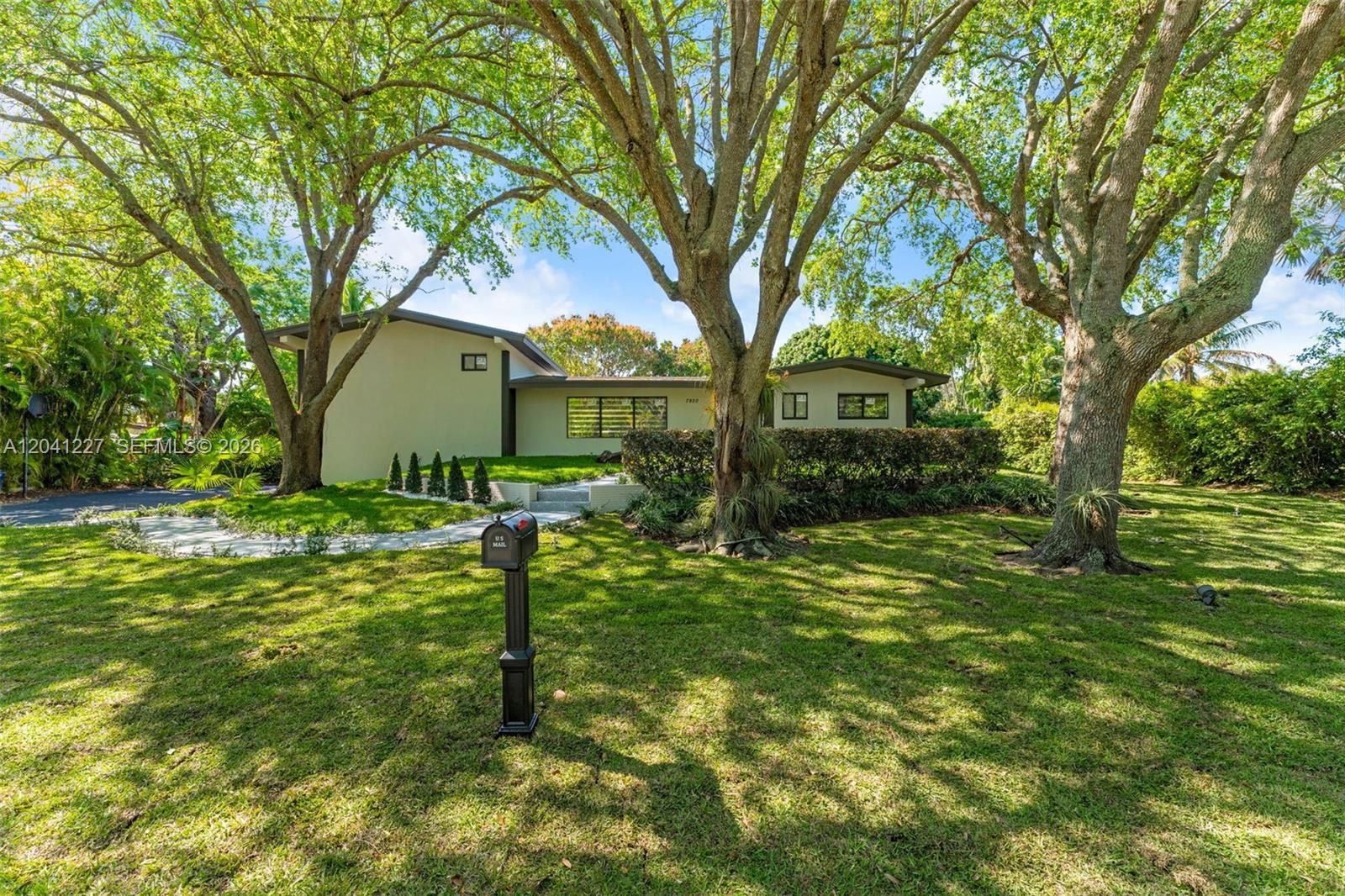 A single-story house with a flat roof is set behind large trees and a lawn — 7920 SW 132nd St # 0, Pinecrest FL 33156, PINECREST, FL