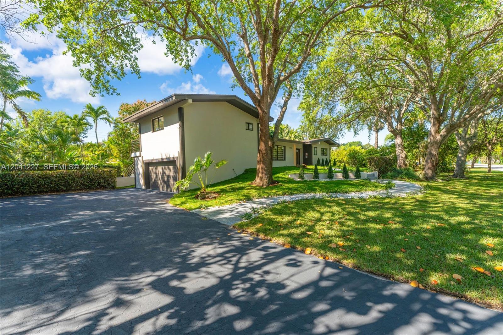 A two-story house with a garage and paved driveway sits on a grassy, tree-lined lot — 7920 SW 132nd St # 0, Pinecrest FL 33156, PINECREST, FL