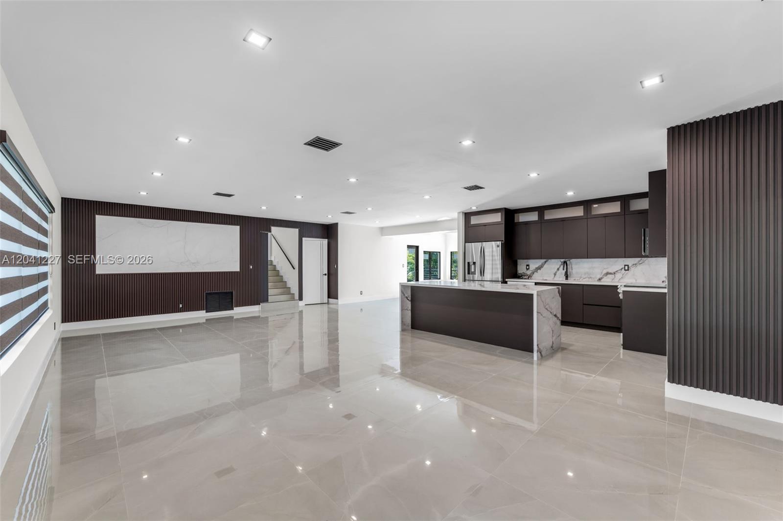A modern open-concept kitchen and living area features dark cabinetry, marble countertops, and tiled floors — 7920 SW 132nd St # 0, Pinecrest FL 33156, PINECREST, FL