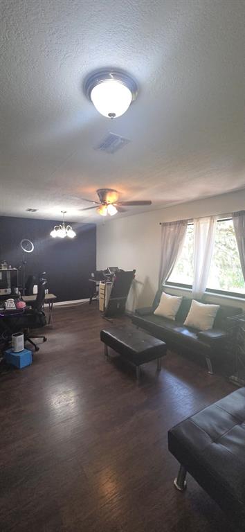 A living room features dark wood flooring, a black accent wall, and a black sofa — 4322 CASAURINA ROAD, LADY LAKE, FL