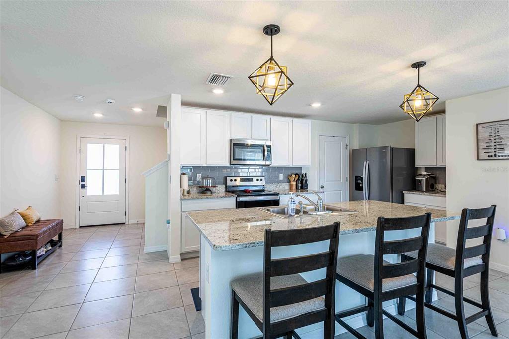 A kitchen features white cabinets, granite countertops, a center island, and two geometric pendant lights — 12172 LILY MAGNOLIA LANE, RIVERVIEW, FL