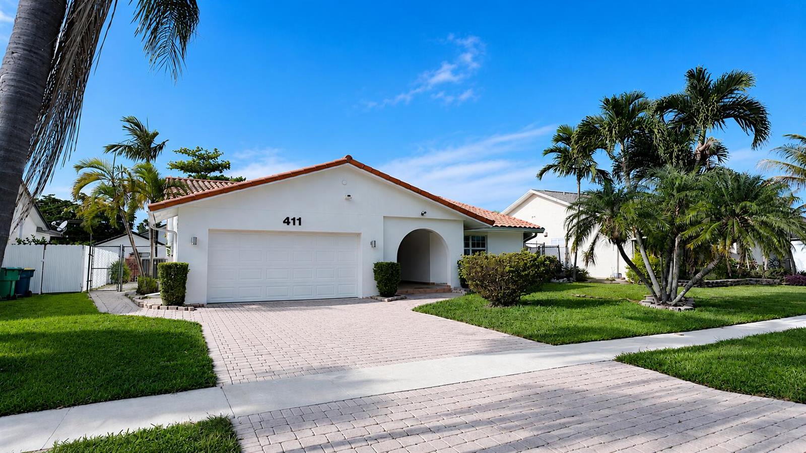 A white single-story house with a tile roof, garage, and paved driveway under a blue sky — 411 SE 4th Street, Dania Beach FL 33004, DANIA BEACH, FL