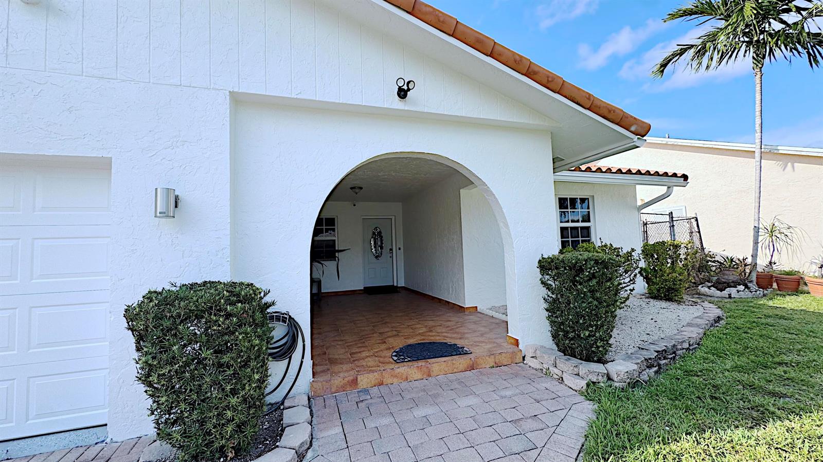 A white house exterior features a tiled entryway with an arched opening and a walkway — 411 SE 4th Street, Dania Beach FL 33004, DANIA BEACH, FL