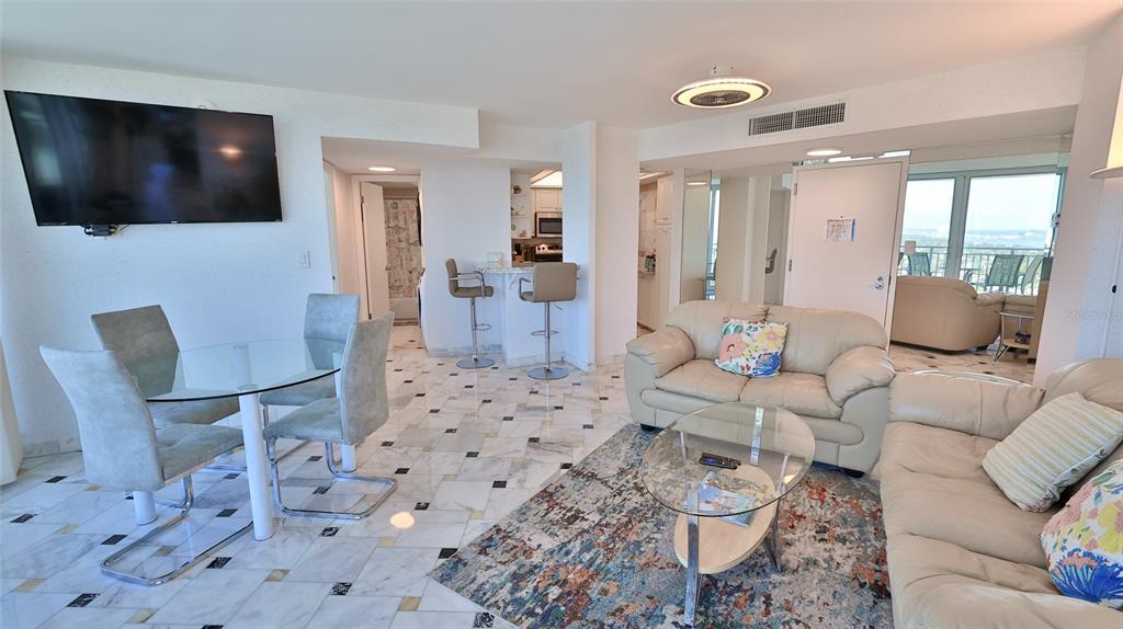 An open-concept living and dining area features marble floors, a glass table, and beige sofas — 2625 S ATLANTIC AVENUE UNIT 24NW, DAYTONA BEACH, FL
