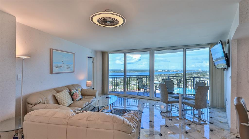 A living and dining area with marble floors, a beige sofa, and floor-to-ceiling windows — 2625 S ATLANTIC AVENUE UNIT 24NW, DAYTONA BEACH, FL