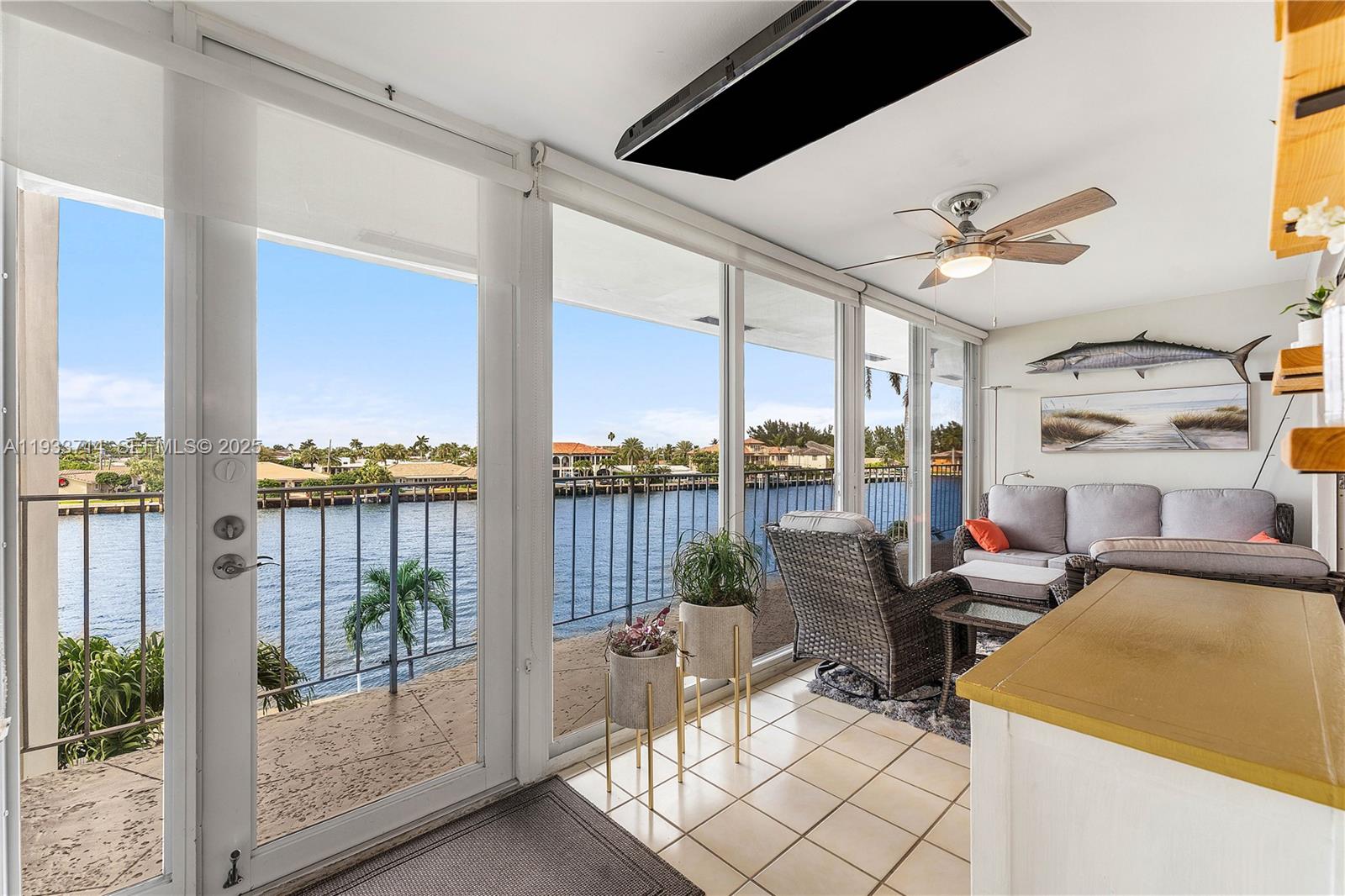 A sunroom features tile flooring, a ceiling fan, and large windows overlooking a waterway — 743 N Riverside Dr # 5C, Pompano Beach FL 33062, POMPANO BEACH, FL