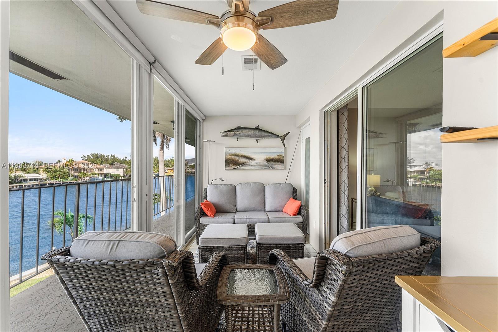 A sunroom with wicker furniture, a ceiling fan, and sliding glass doors overlooking a canal — 743 N Riverside Dr # 5C, Pompano Beach FL 33062, POMPANO BEACH, FL