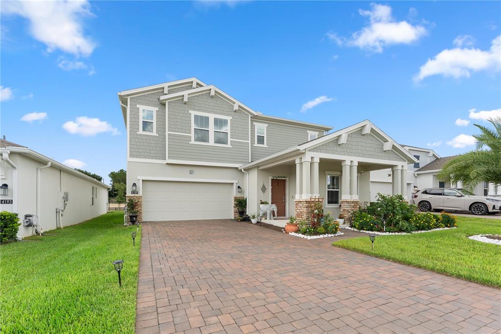 A two-story suburban house with a paved driveway, a covered porch, and light green siding — 4189 JESPERSEN STREET, APOPKA, FL