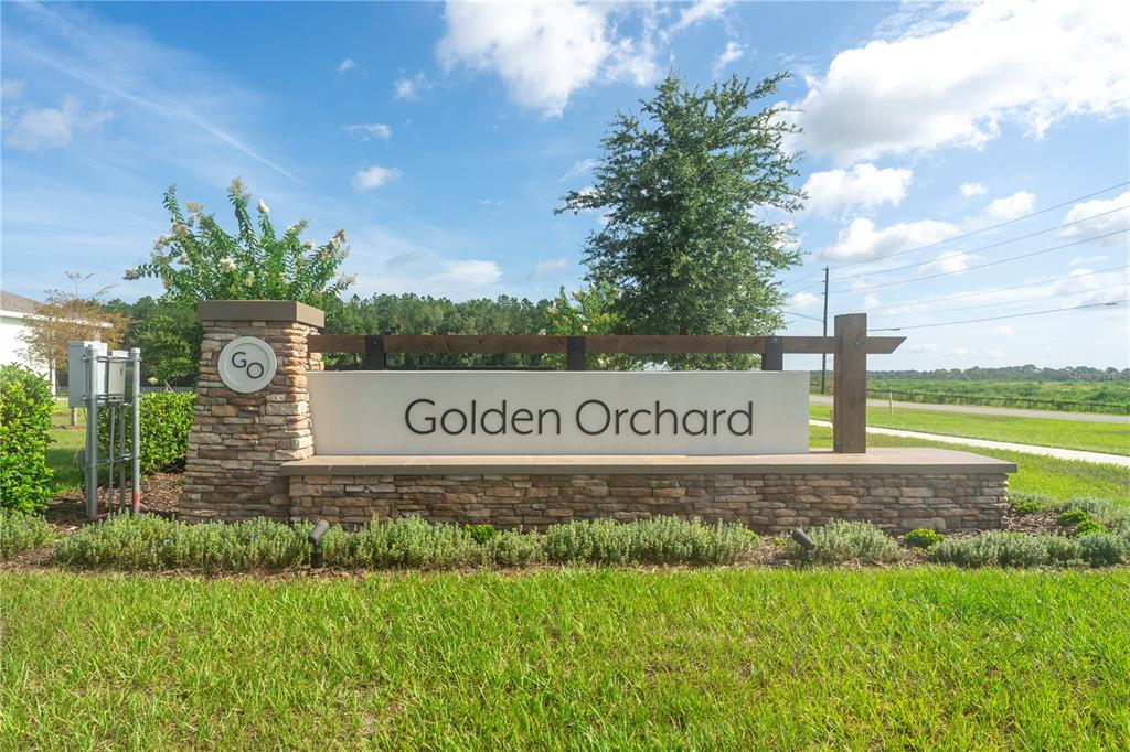 A stone and concrete monument sign for Golden Orchard stands in a grassy field — 4189 JESPERSEN STREET, APOPKA, FL