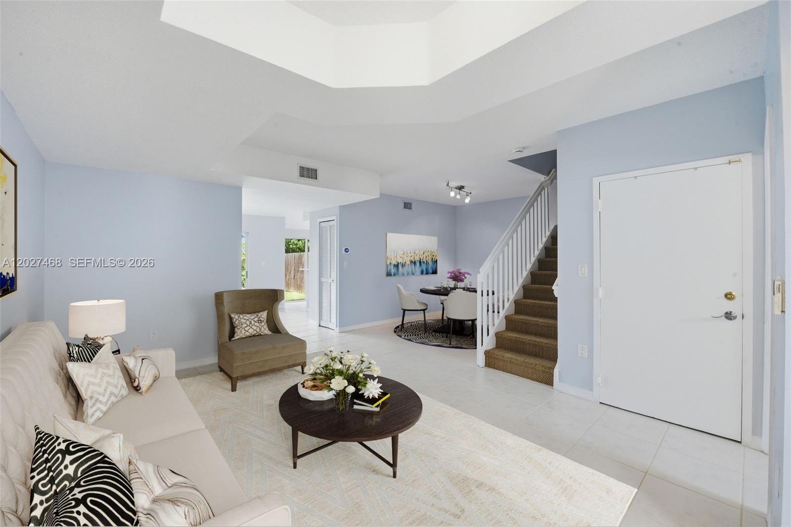 A living room with light blue walls, tile flooring, a staircase, and a dining area — 10180 SW 88th St # 403, Miami FL 33176, MIAMI, FL