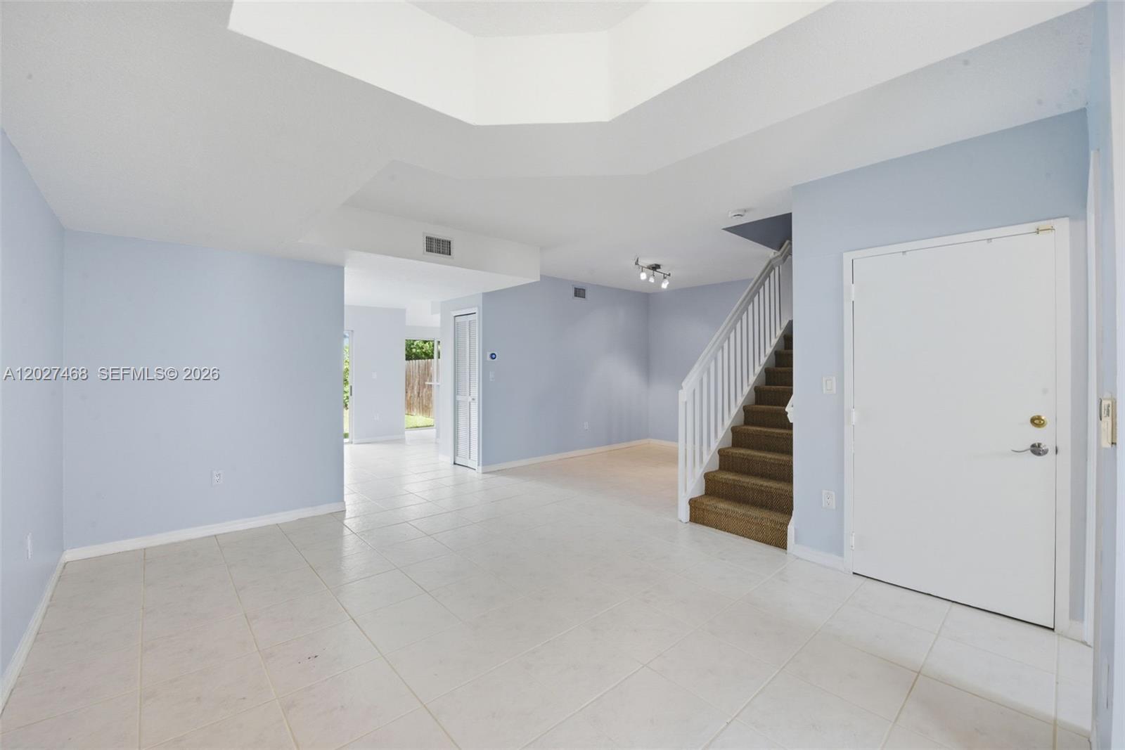 An interior view shows a tiled living area with a staircase and light blue walls — 10180 SW 88th St # 403, Miami FL 33176, MIAMI, FL