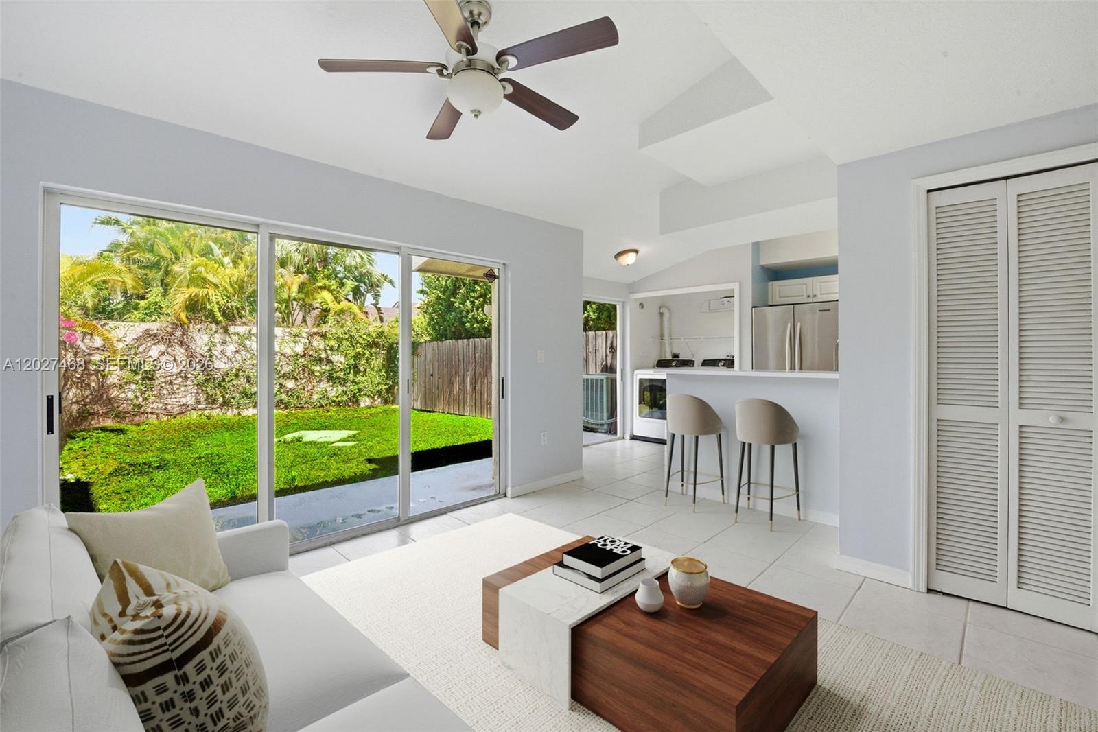 A living room features a ceiling fan, sliding glass doors to a yard, and a kitchen — 10180 SW 88th St # 403, Miami FL 33176, MIAMI, FL