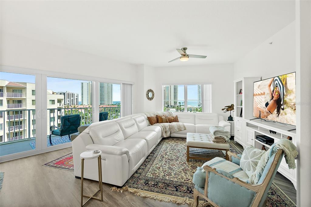 A bright living room features a white sectional sofa, patterned area rug, and balcony views — 2 OCEANS WEST BOULEVARD UNIT 606, DAYTONA BEACH SHORES, FL