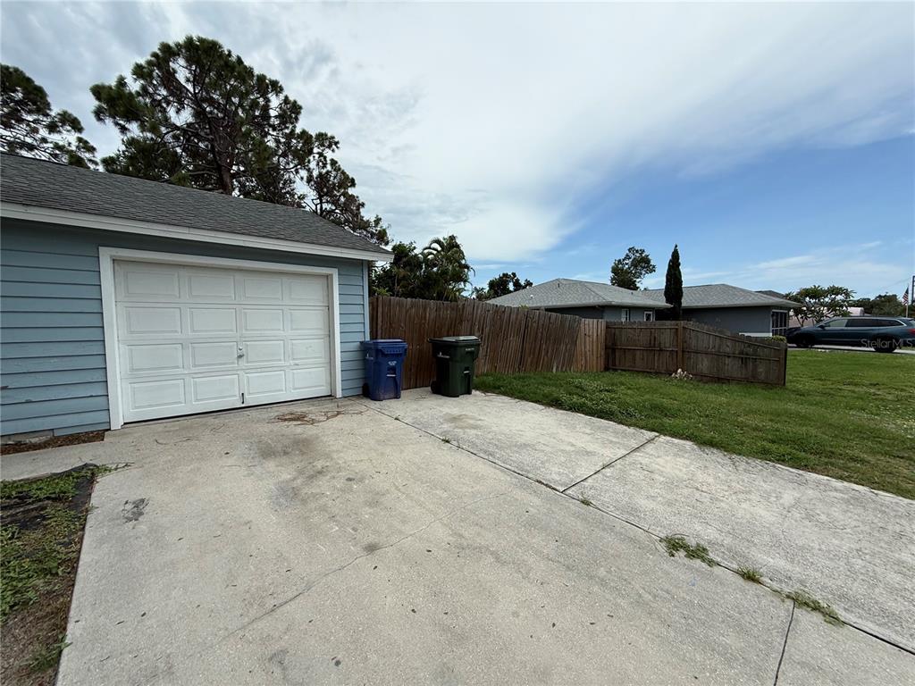 A blue house with a white garage door, a concrete driveway, and a wooden fence — 855 JAMAICA ROAD, VENICE, FL