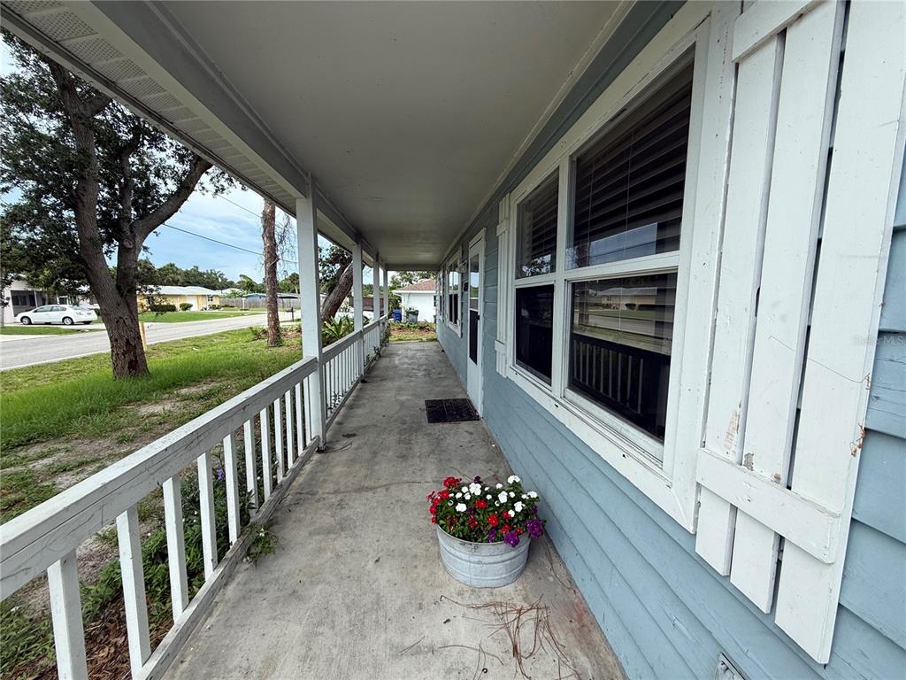 A covered front porch with a concrete floor, white railings, and a potted flower arrangement — 855 JAMAICA ROAD, VENICE, FL