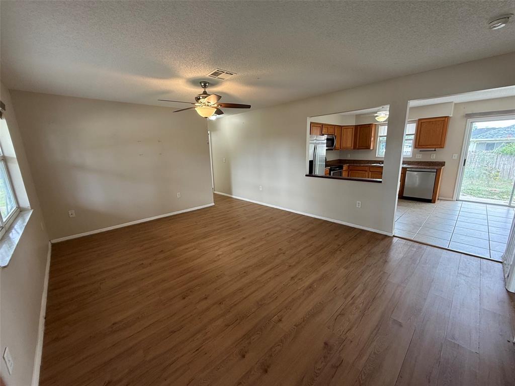 An open-concept living room features wood-look flooring, a ceiling fan, and a kitchen pass-through window — 855 JAMAICA ROAD, VENICE, FL