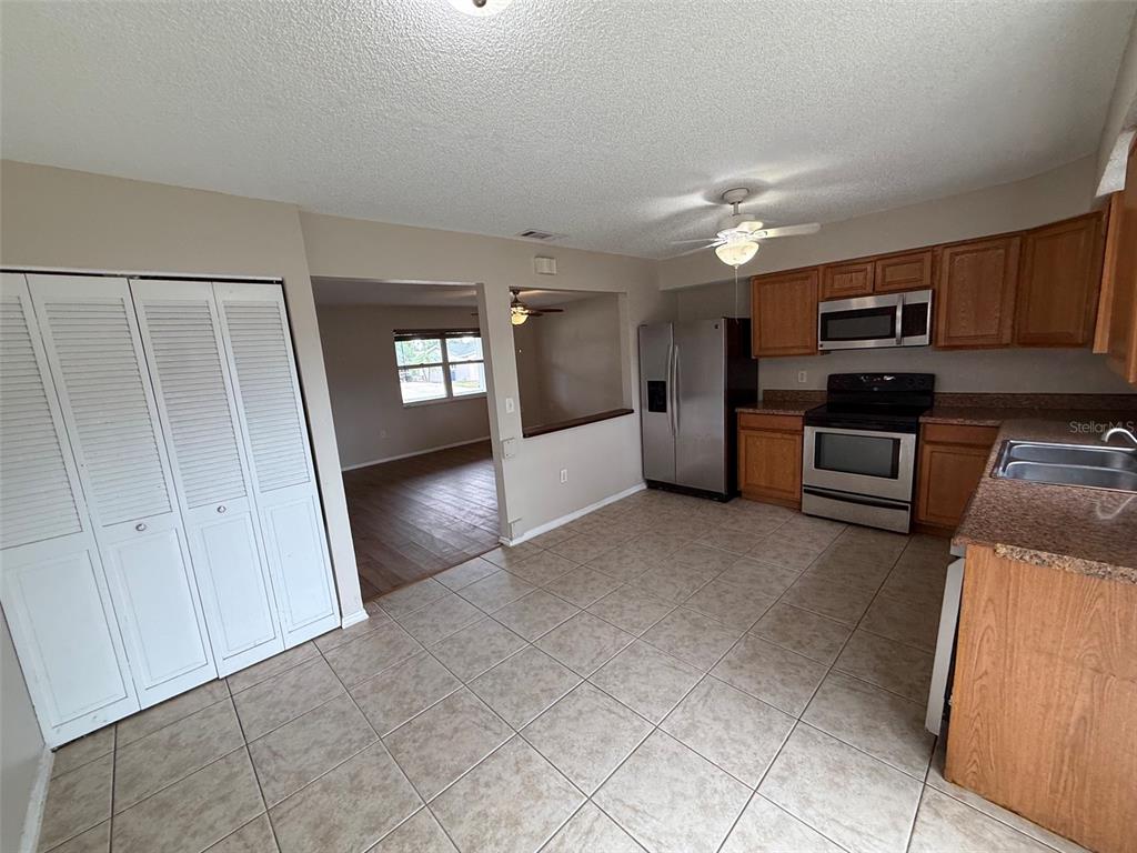 A kitchen with tile flooring, wood cabinets, stainless steel appliances, and a view into another room — 855 JAMAICA ROAD, VENICE, FL