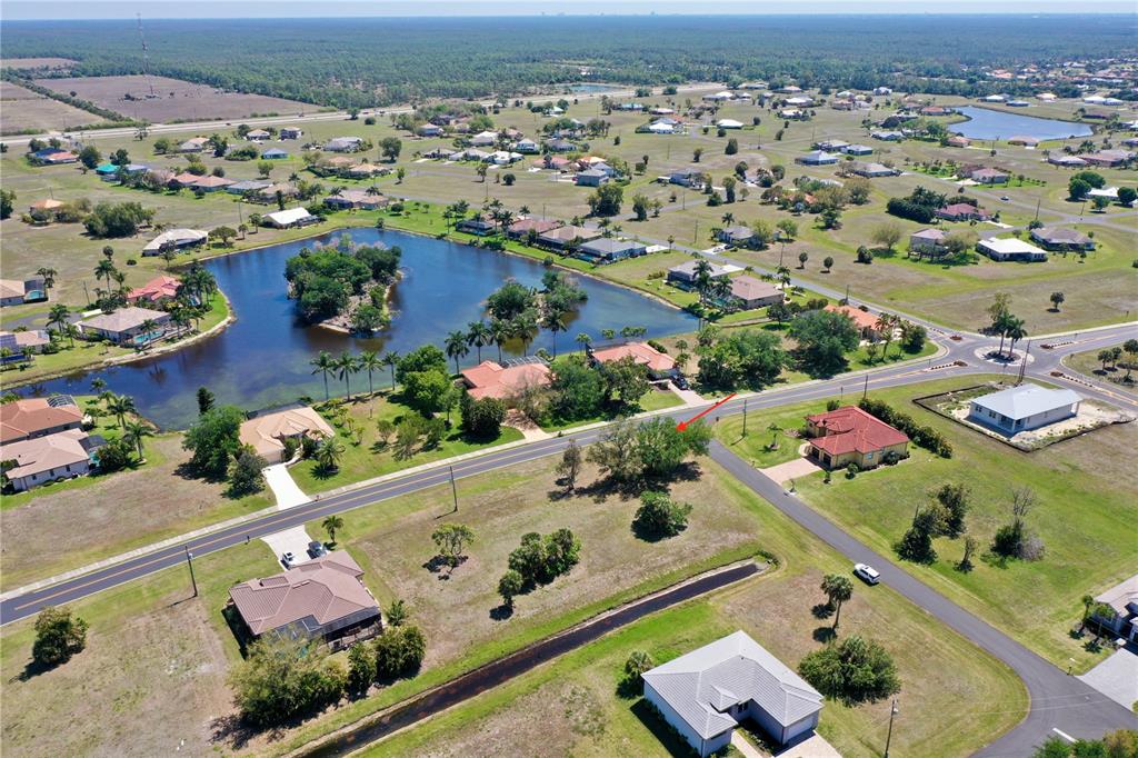An aerial view shows a suburban neighborhood with scattered houses, a lake, and paved roads — 17175 CAPE HORN BOULEVARD, PUNTA GORDA, FL