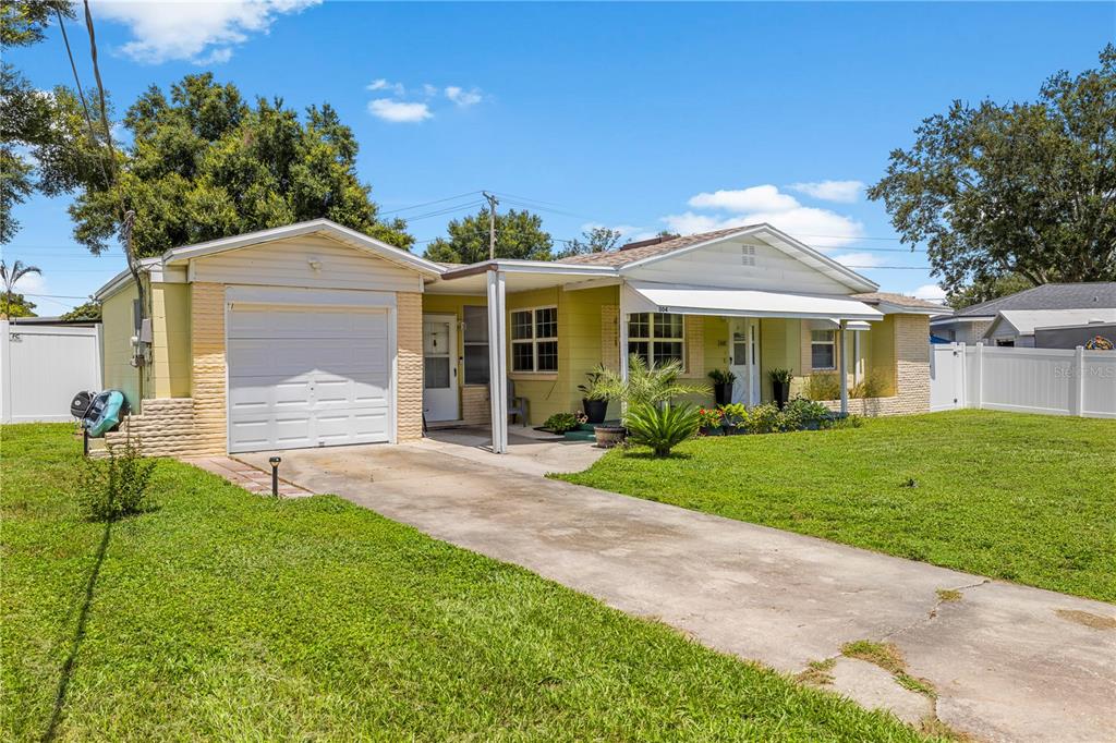 A single-story yellow house with a white garage, a concrete driveway, and a front porch — 304 W LAKE AVENUE, AUBURNDALE, FL
