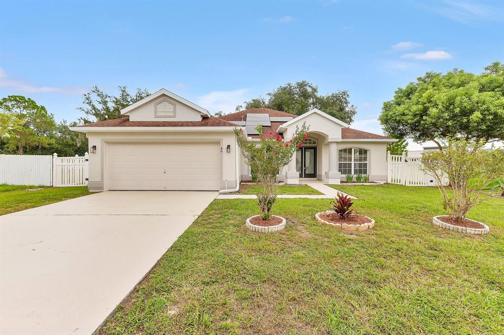 A single-story house with a tan stucco exterior, a two-car garage, and rooftop solar panels — 46 CORDONA DRIVE, KISSIMMEE, FL