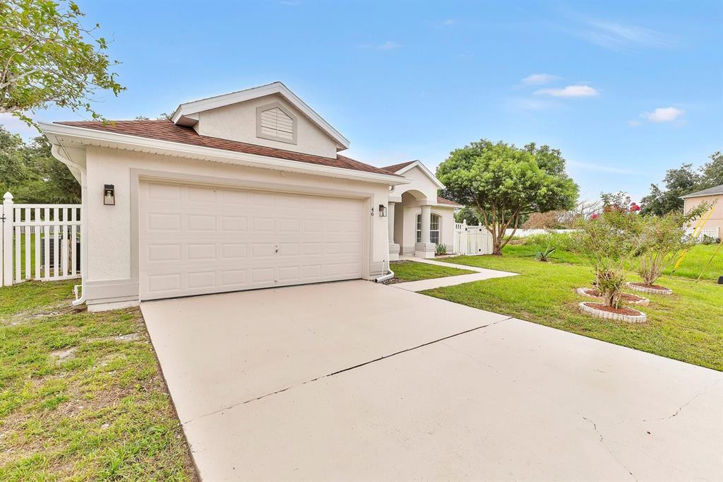 A single-story house with a tan stucco exterior, a brown shingled roof, and solar panels — 46 CORDONA DRIVE, KISSIMMEE, FL