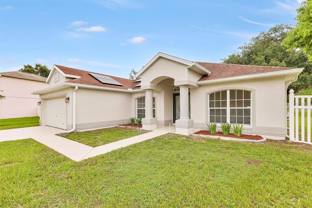 A single-story house with a two-car garage, a front lawn, and a white fence — 46 CORDONA DRIVE, KISSIMMEE, FL