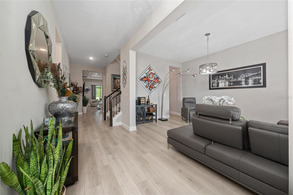 A living area with light wood flooring, a grey sectional sofa, and a staircase — 5128 BREEZY ACRES STREET, WINTER GARDEN, FL