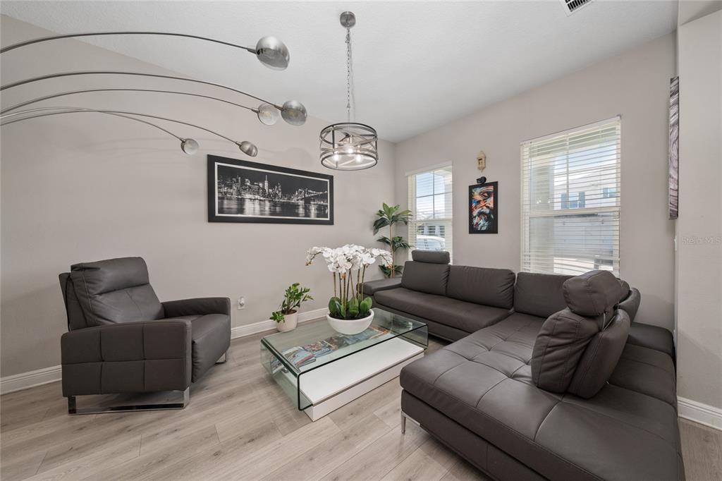 A living room features gray leather furniture, a glass coffee table, and a modern floor lamp — 5128 BREEZY ACRES STREET, WINTER GARDEN, FL