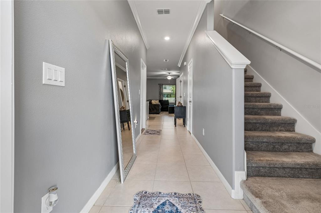 A hallway with tile flooring, a leaning mirror, and a carpeted staircase leading upward — 21851 LYONIA LANE, LAND O LAKES, FL