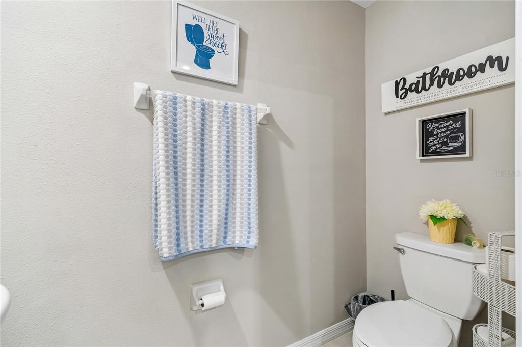 A bathroom features a towel rack, toilet, and wall decor with humorous text — 21851 LYONIA LANE, LAND O LAKES, FL