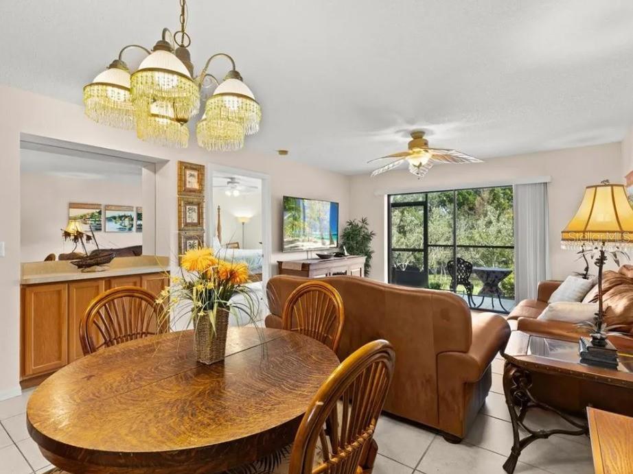 A dining area with a wooden table opens into a living room with leather furniture — 1669 SEASCAPE CIRCLE UNIT 1669, TARPON SPRINGS, FL