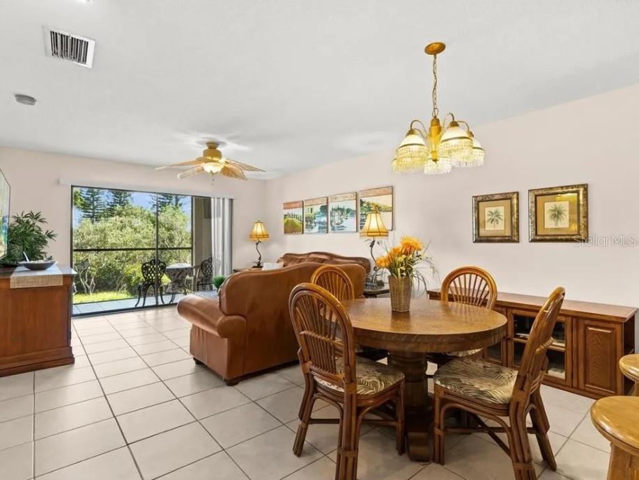 A dining area and living room with tile floors, a ceiling fan, and a sliding glass door — 1669 SEASCAPE CIRCLE UNIT 1669, TARPON SPRINGS, FL