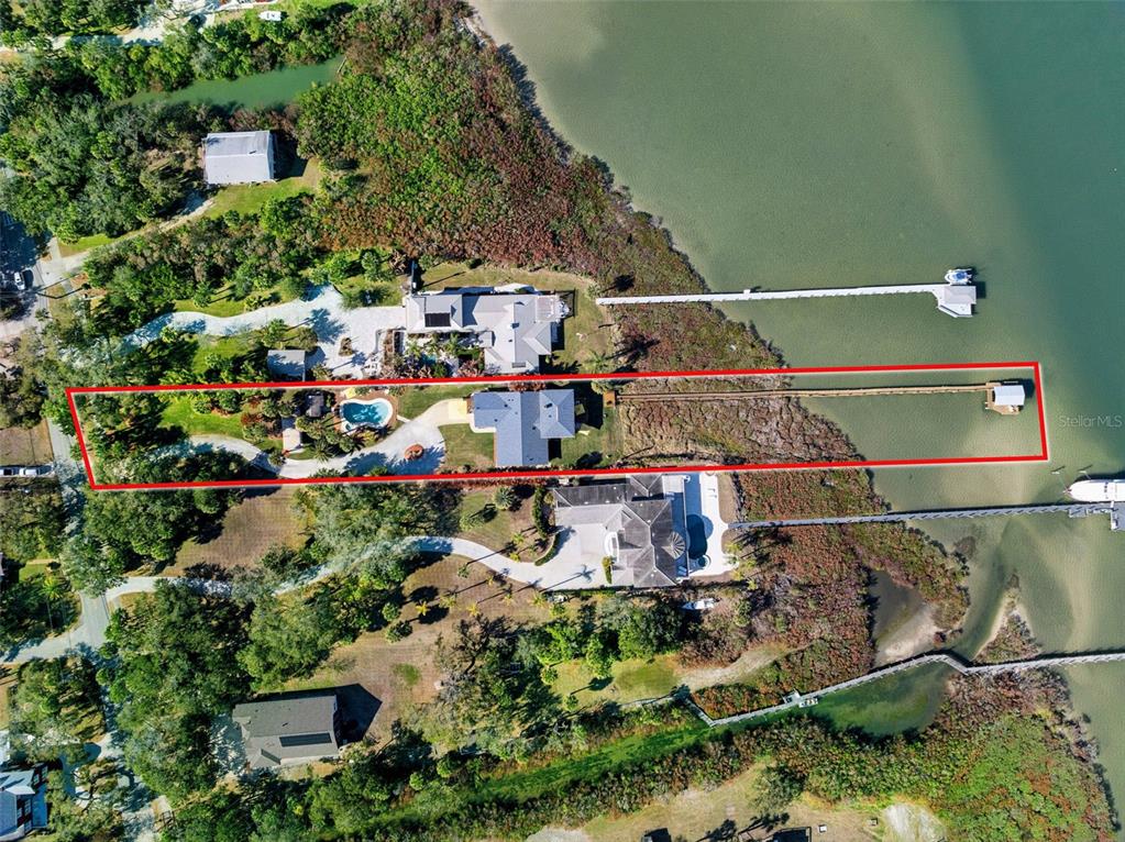 An aerial view shows a waterfront property outlined in red, featuring a house, pool, and dock — 1703 S RIVERSIDE DRIVE, NEW SMYRNA BEACH, FL