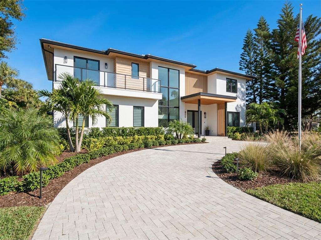 A two-story modern house with a paved driveway, white stucco walls, and wood accents — 1703 S RIVERSIDE DRIVE, NEW SMYRNA BEACH, FL
