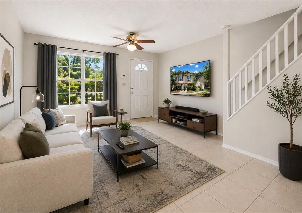 A living room features a sofa, coffee table, television, and stairs with white railings — 2316 FLETCHERS POINT CIRCLE, TAMPA, FL