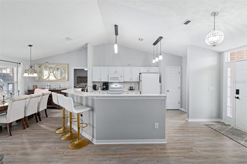 A kitchen with white cabinets, a breakfast bar, and light wood-look flooring — 23 POWDER HILL LANE, PALM COAST, FL