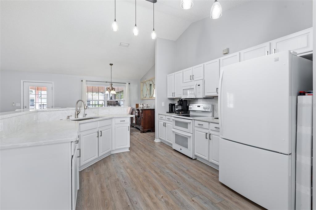 A kitchen with white cabinets, light countertops, stainless steel appliances, and wood-look flooring — 23 POWDER HILL LANE, PALM COAST, FL
