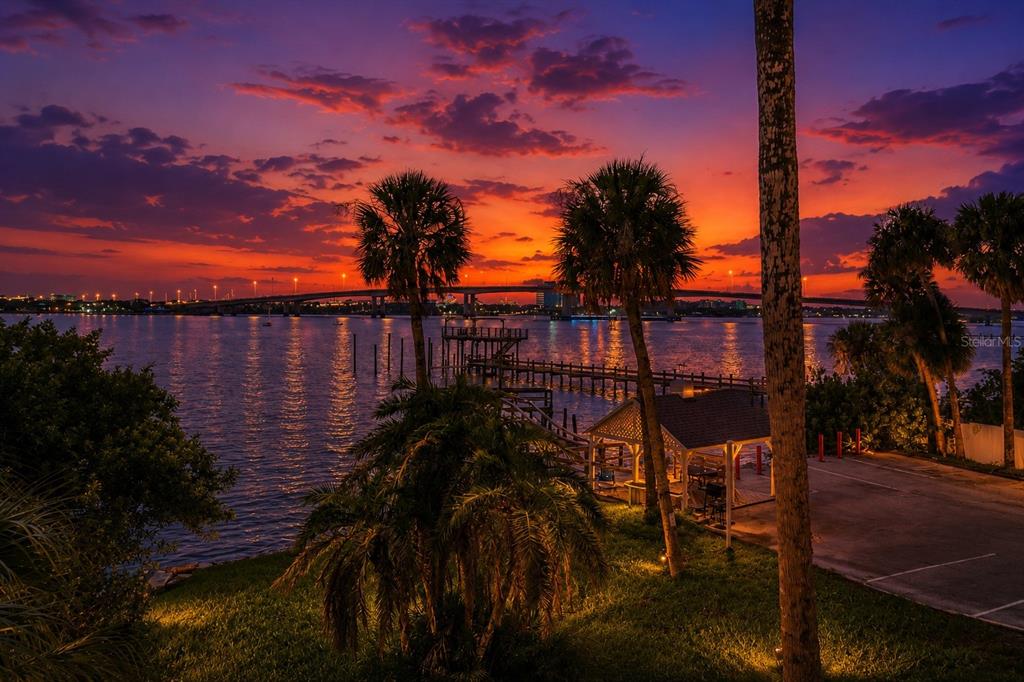 A sunset view over a bay with a bridge, a wooden pier, and palm trees — 900 S PENINSULA DRIVE UNIT 214, DAYTONA BEACH, FL