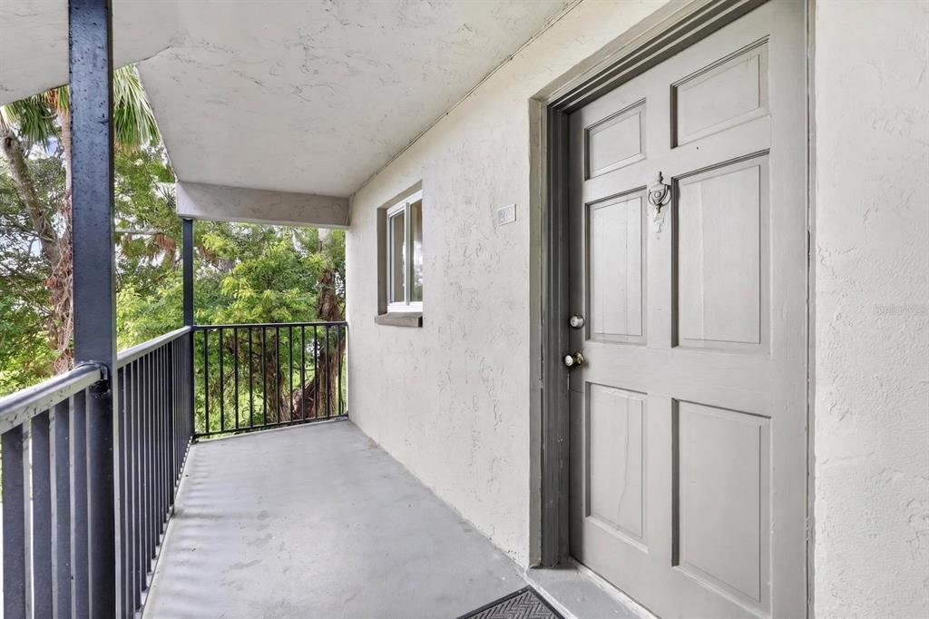 A gray front door with a knocker opens onto a covered balcony with black railings — 900 S PENINSULA DRIVE UNIT 214, DAYTONA BEACH, FL