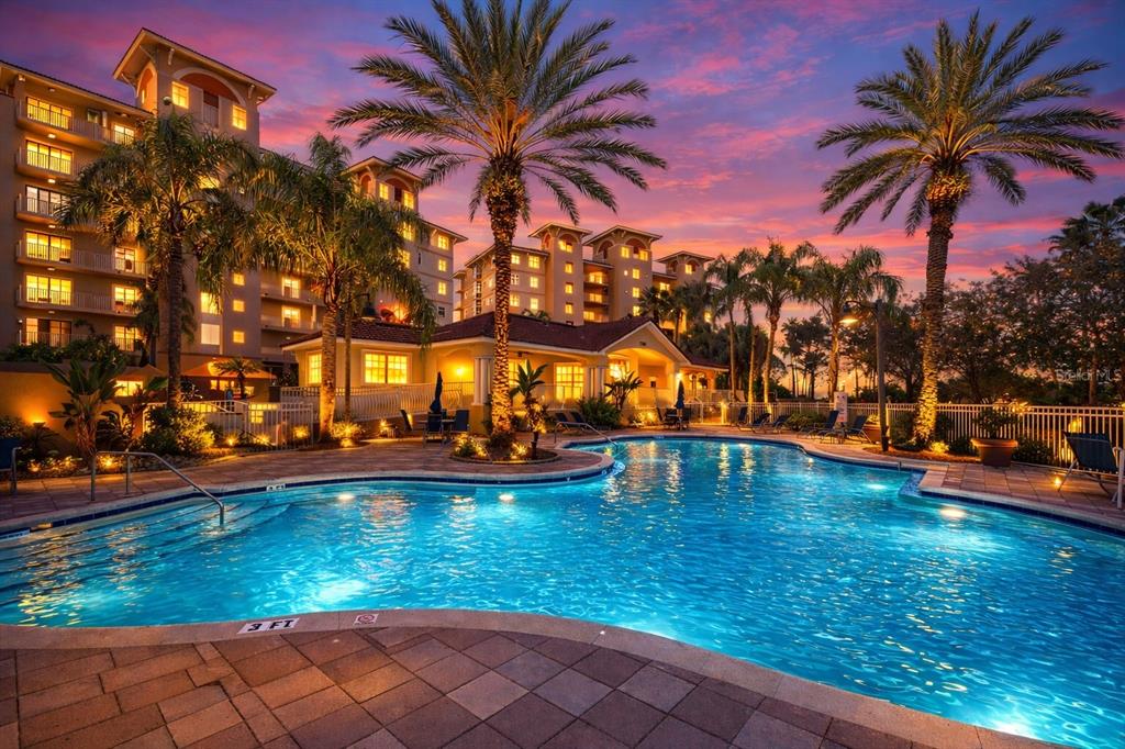 A swimming pool with a shallow end sits in front of a multi-story apartment building — 12033 GANDY BOULEVARD N UNIT 133, ST PETERSBURG, FL