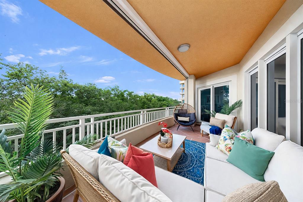 A furnished balcony features a white sectional sofa, a coffee table, and a scenic view — 12033 GANDY BOULEVARD N UNIT 133, ST PETERSBURG, FL